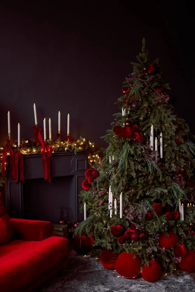 Christmas mantle ideas with candles: dark mantel with taper candles, red ribbon and a red Christmas tree