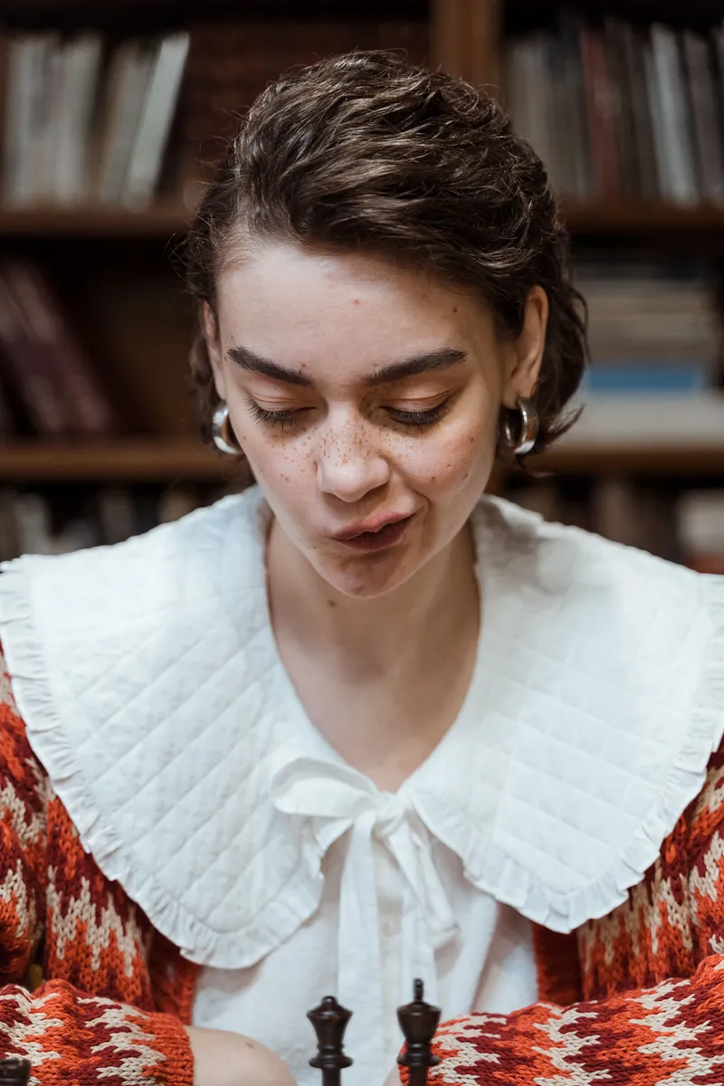 Woman in a white quilted collar with a bow over a red and white patterned knit, a Christmas Eve sweater outfit